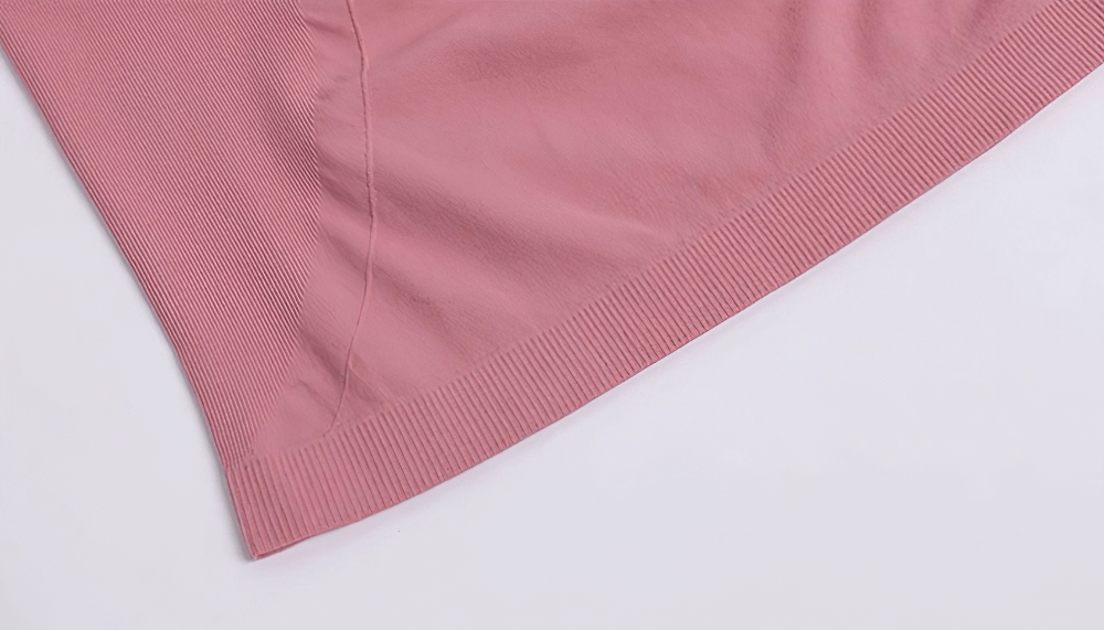 Close-up of pink breathable nylon fabric, featuring ribbed hem details of a short-sleeve fitness t-shirt.